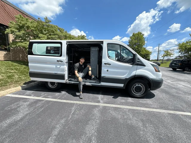 TAS technician seated beside the open door of a service van