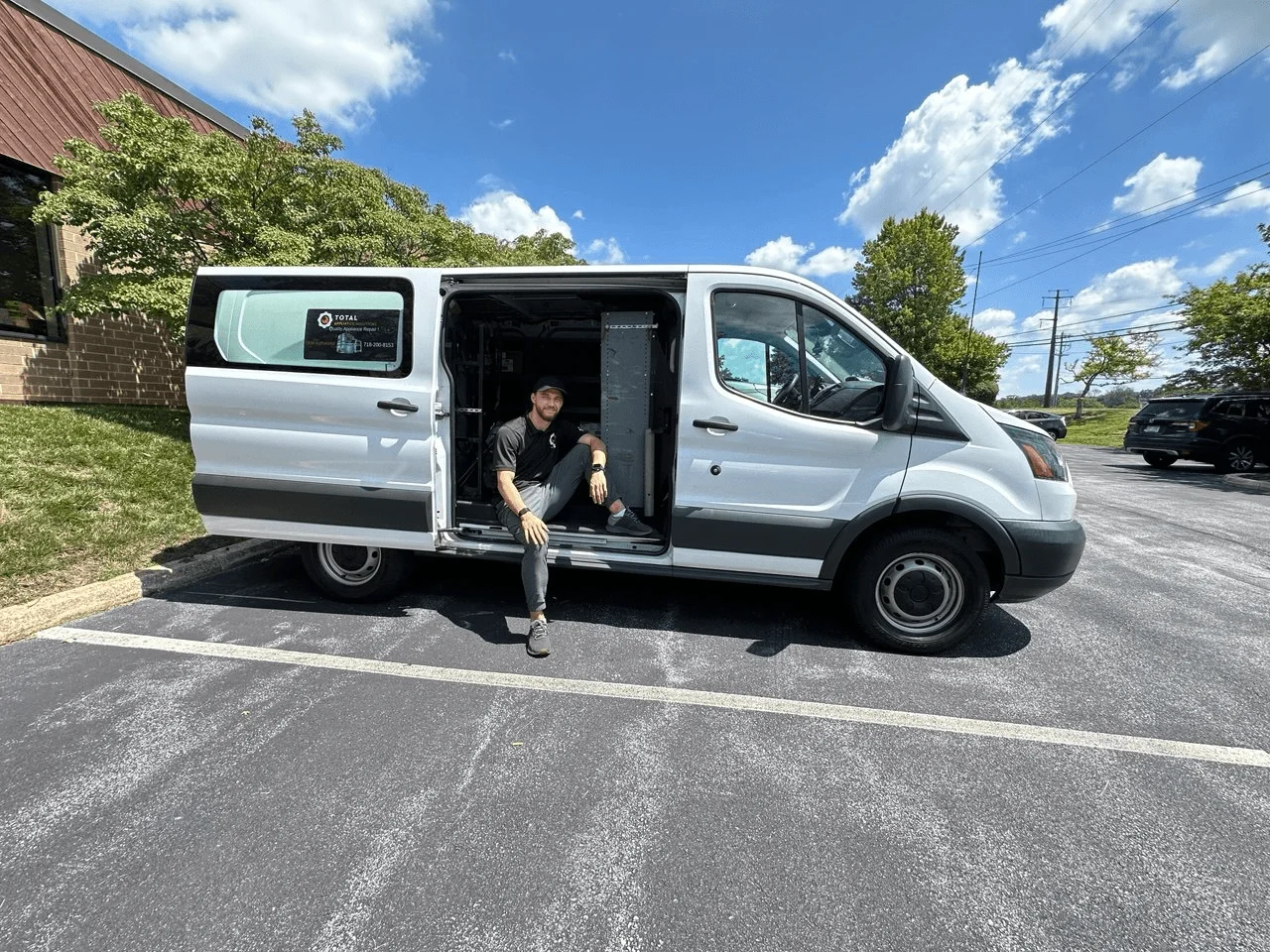 TAS technician seated beside the open door of a service van